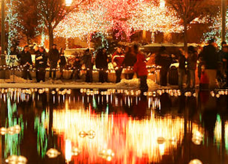 Hundreds of visitors wander as they look over Christmas lights on the reflecting pond at Temple Squa