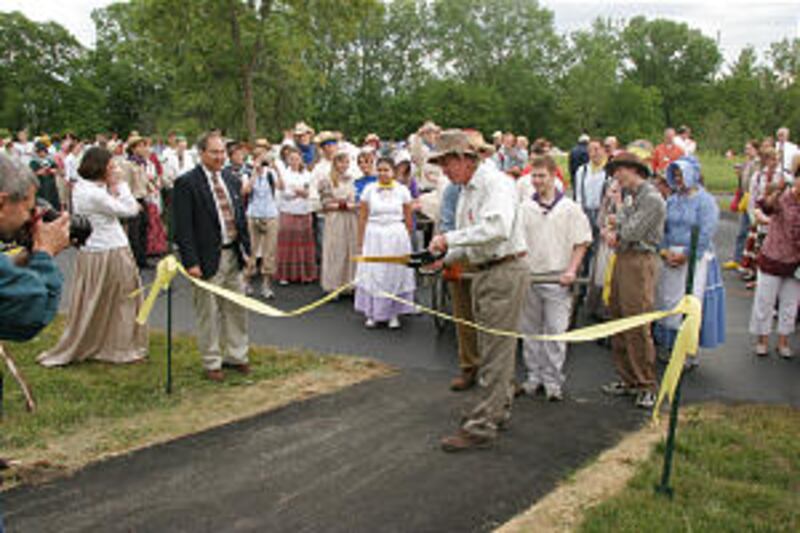Paul Willie cuts ribbon to signal start of youth handcart trek at Mormon Handcart Park in Coralville