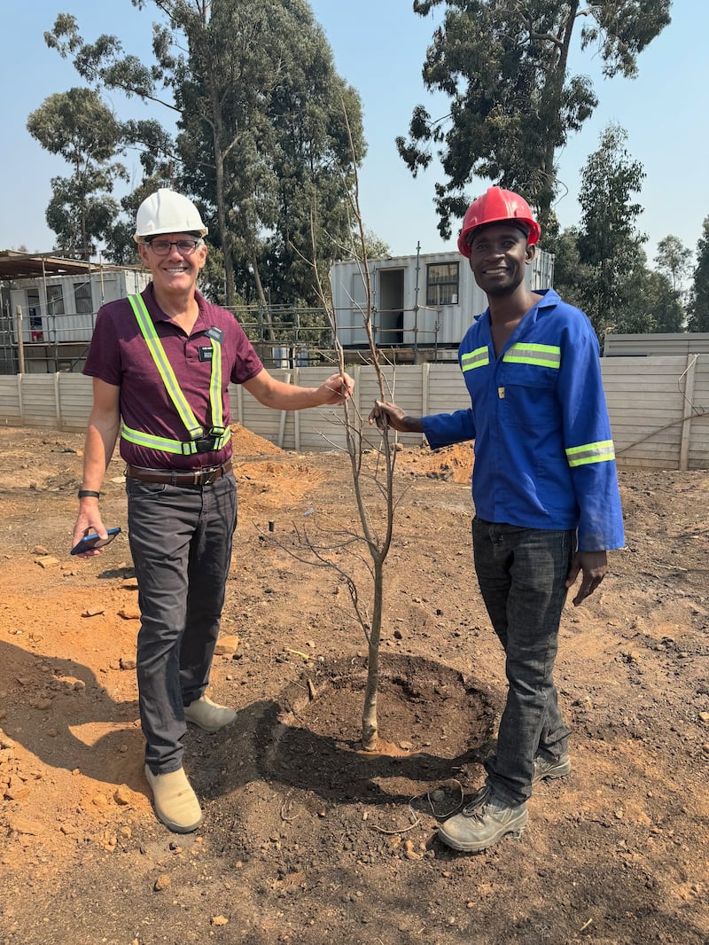 Elder Bruce Anderson and Kilford Shereni stand beside a sapling tree on the Harare Zimbabwe Temple grounds.