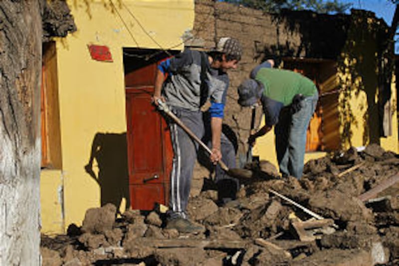 Young men clean up rubble outside the home of a member near El Monte, Chile. Some 400 members lost t