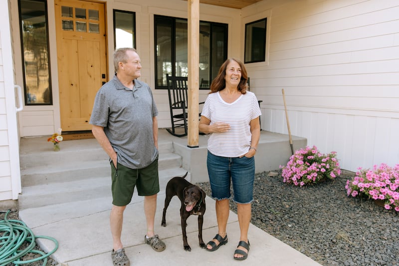 Standing outside with their dog Mia, Todd and Debbie Rogers tell the story of their home surviving the Spokane wildfires in Spokane, Washington, on Saturday, Aug. 22, 2026.